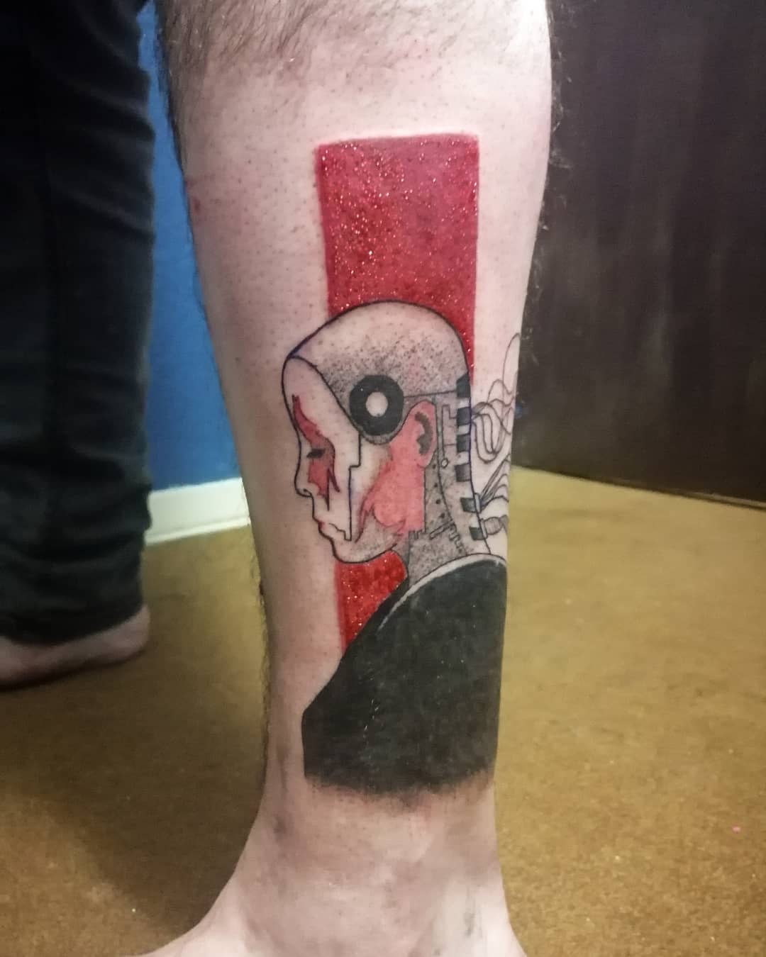 Minimalist cyberpunk tattoo on lower leg featuring a stylized profile of a female cyborg with a bold red background
